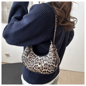 Detailed side view of a large leopard print hobo bag worn by a model on a white background
