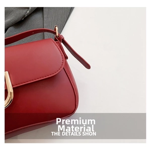Close-up of red matte leather shoulder bag with golden U-shaped metal buckle detail