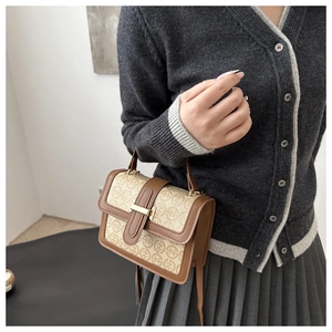 Detail of vintage brown satchel with letter print and gold hardware buckle