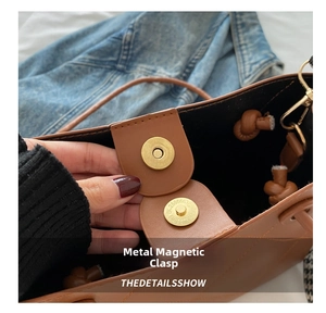 Détail du fermoir magnétique doré sur un sac à main en cuir marron avec doublure noire