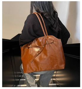 Detail of dark brown vintage leather tote featuring stylish decorative buckle and straps