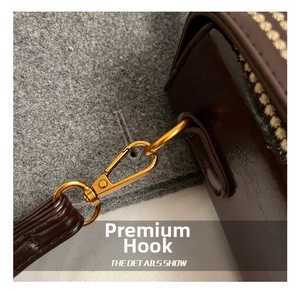Close-up of golden lobster clasp and brown leather strap on a stylish handbag