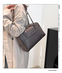 Detail of deep brown leather tote with front pocket and zipper on a model's shoulder