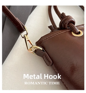 Detailed close-up of golden metal hardware hook on brown retro leather handbag