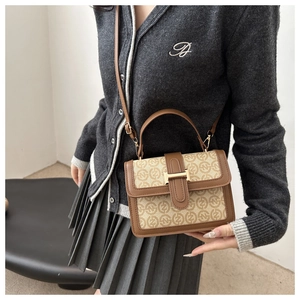 Detail shot of vintage brown flap square bag with H-buckle worn by a model in gray outfit