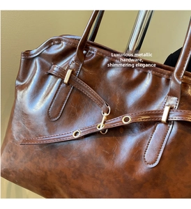 Detailed close-up of glossy deep brown tote bag with premium light gold hardware rings