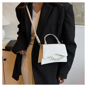 Detailed view of the white minimalist crossbody bag with gold chain and metal hardware buckle