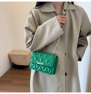 Detail of green quilted crossbody bag with gold chain strap and metallic clasp on a model
