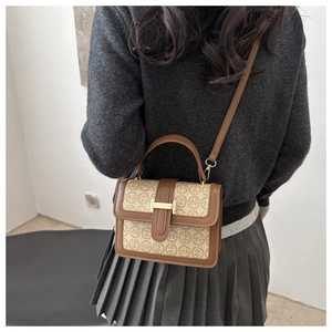 Lifestyle shot showing the retro monogram print handbag worn by a model in casual attire
