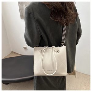 Détail du sac cabas matelassé blanc avec bandoulière pied-de-poule portée par un mannequin