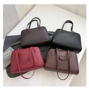 Four large tote bags in black, burgundy, dark brown and tan displayed on soft white fabric