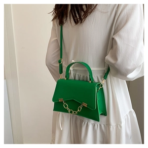 Détail du sac bandoulière en cuir vert émeraude avec rabat en V et chaîne dorée