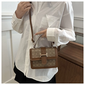 Close-up of a stylish crossbody bag with vintage print and gold buckle on a model