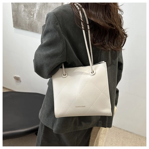 Détail du sac fourre-tout crème matelassé avec large bandoulière porté par un mannequin