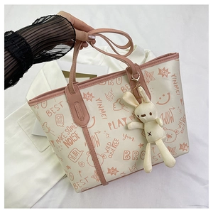 Detail of tote bag with graffiti prints, pink leather trim and a plush bunny charm