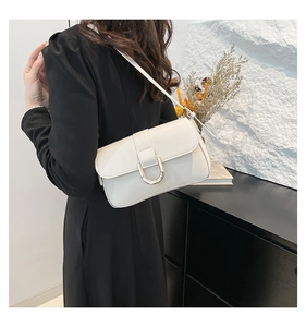 Detailed close-up of white leather baguette bag with premium golden horseshoe buckle