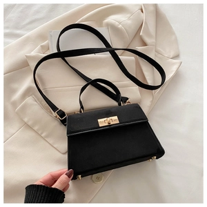 Close-up of black matte suede Kelly bag with golden twist lock and protective metal feet