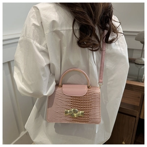 Detailed view of pink crocodile-embossed mini bag with golden wave metallic clasp