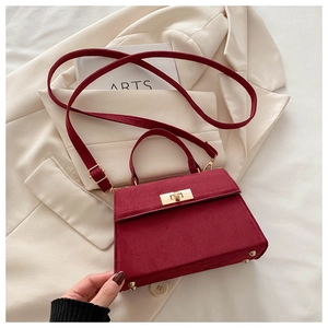 Macro detail of wine red matte suede bag featuring gold metal turn-lock and handle