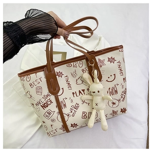 Detailed close-up of large graffiti tote bag with brown straps and cute bunny charm