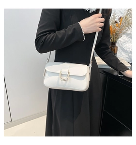 Detail of cream-colored shoulder bag featuring a prominent gold U-shaped metal buckle