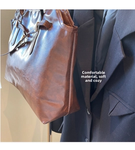 Close-up of vintage brown leather tote bag with belt buckle detail and soft texture