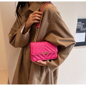 Detail of bright pink quilted crossbody bag with gold chain and metal twist lock