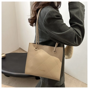 Détail du cabas matelassé beige avec texte 'FASHION & BAGS' porté à l'épaule
