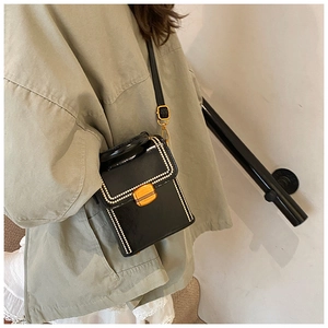 Retro black glossy leather square bag with white dotted stitching shown worn crossbody