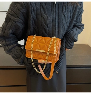 Close-up of caramel brown quilted shoulder bag with geometric stitching and gold chain