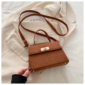 Detailed view of brown suede satchel with golden buckle and protective base studs