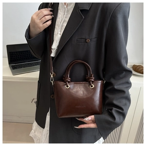 Detailed close-up of dark brown vintage leather bucket bag with top handle and gold rings