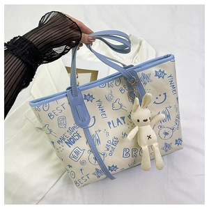 Close-up of contrast-colored tote bag with blue graffiti prints and cute bunny pendant
