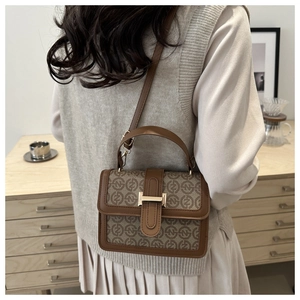 Detail view of khaki monogram canvas handbag with brown leather trim and gold metal lock