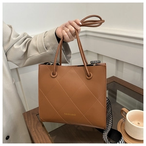 Détail d'un sac cabas marron matelassé avec bandoulière pied-de-poule et lettrage