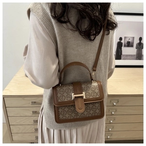 Detail view of vintage brown monogram handbag with adjustable strap shown in home setting