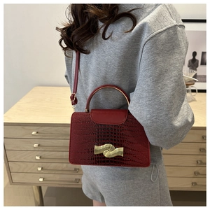 Detail of red croc-embossed small square bag with unique gold metal arch handle