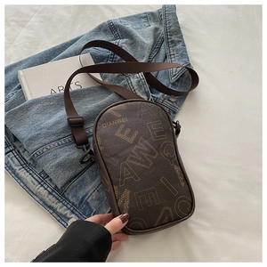 Detailed close-up of dark brown crossbody bag with letter print and wide fabric strap