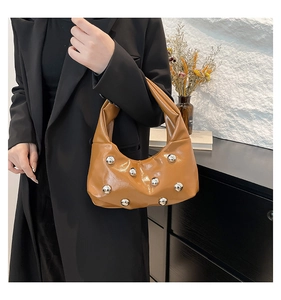 Détail du sac hobo croissant caramel avec grands clous en métal argenté sur cuir verni