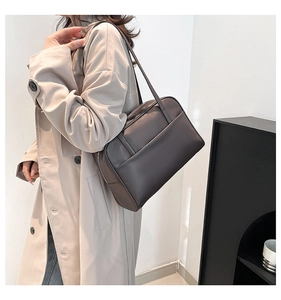 Close-up of a vintage dark brown matte leather shoulder bag worn by a model