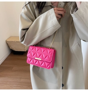 Close-up of vibrant magenta quilted shoulder bag with gold chain and metal bar detail