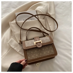 Detail of retro printed square bag with golden buckle on a beige blazer setting