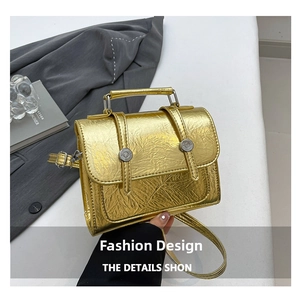 Gros plan d'un mini sac à main doré métallisé froissé avec des boucles argentées