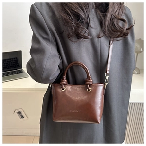 Brown leather bucket bag with knotted handle detail and adjustable crossbody strap