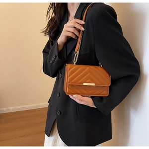 Close-up of brown quilted faux leather shoulder bag with golden chain and metal lock
