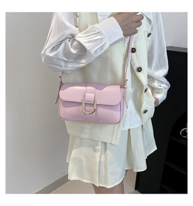 Detail of pink PU leather shoulder bag featuring a gold horseshoe metal buckle and slim strap