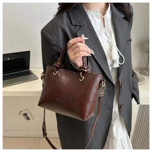 Detail of dark brown leather bucket bag with knotted handle and fashion engraving