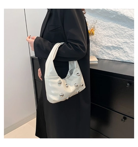 Gros plan du sac sous l'aisselle plissé blanc avec clous argentés porté par un mannequin