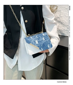 Dettaglio borsa a catena in denim patchwork con trama invecchiata e finiture oro