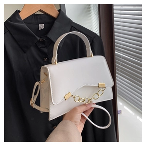 Détail d'un sac à main blanc en cuir avec chaîne dorée et poignée supérieure